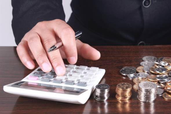 Man calculating life insurance in retirement in a suit at his desk, with coins on it