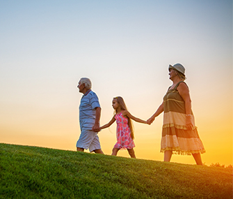 grandparents holding hands with their granddaughter while the sun sets behind them annuity benefits