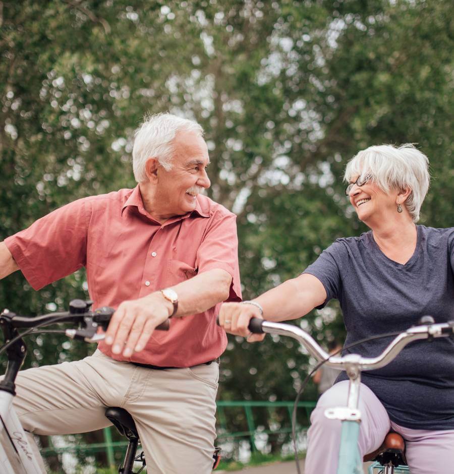 Mature couple riding bicycles in the park and discussing annuity income
